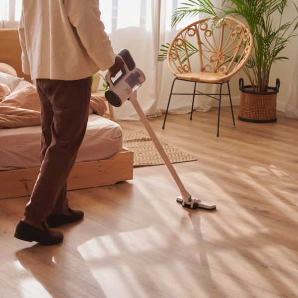 Vacuuming an LVP floor in a sunny bedroom