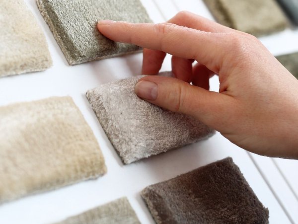 Hand selecting carpet samples on a white display board