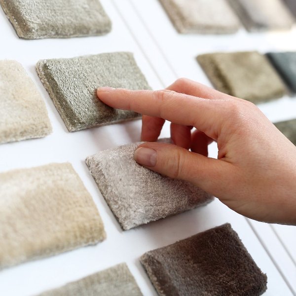 Hand selecting carpet samples on a white display board